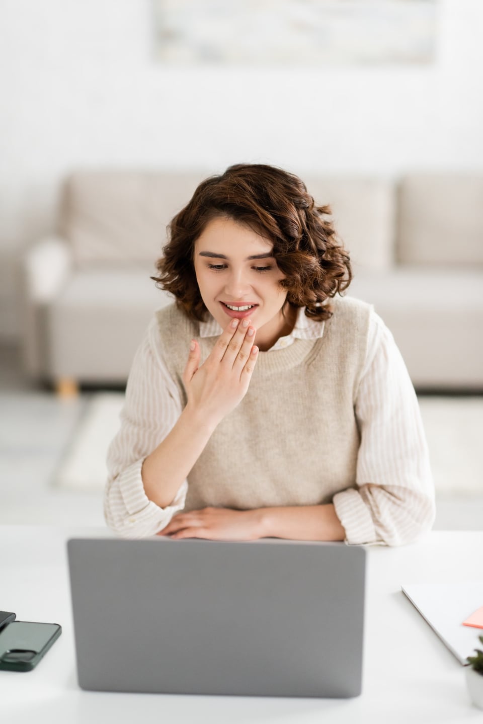 Woman signing while using a laptop at a desk