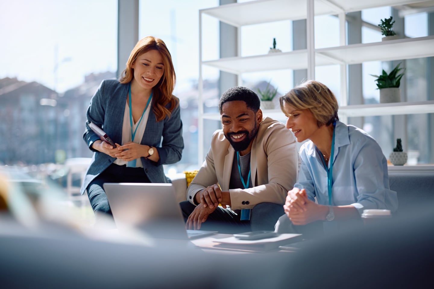 Three colleagues collaborating around a laptop in a bright office