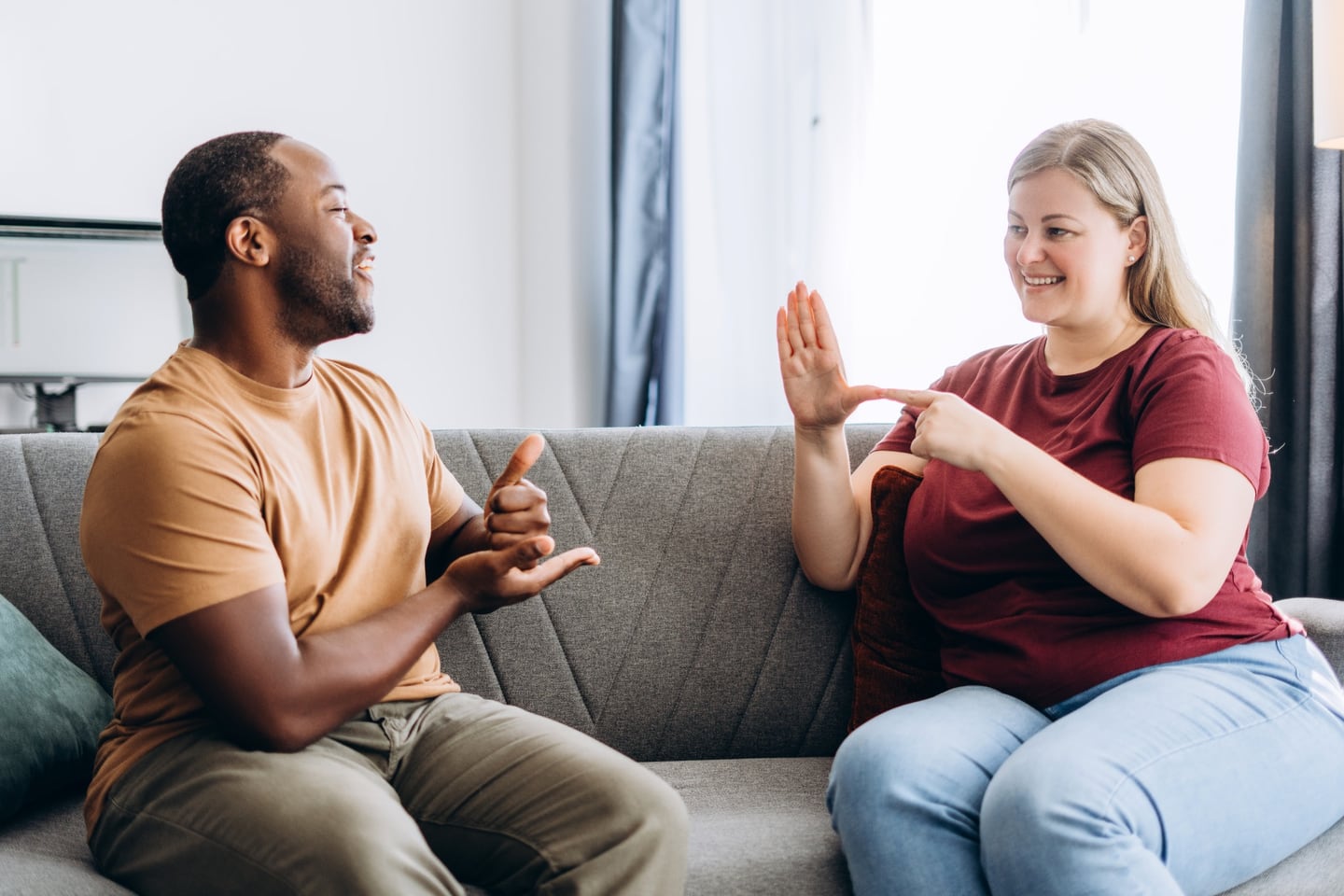 Two adults communicating in sign language in a living room